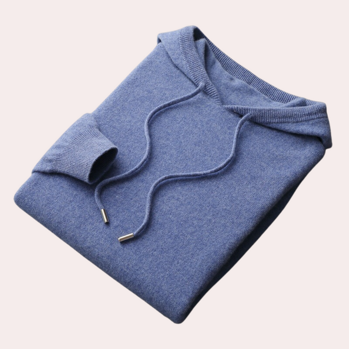 Blauwe gebreide hoodie met capuchon en trekkoorden, opgevouwen op een lichte achtergrond. Comfortabele herenkleding, casual stijl.