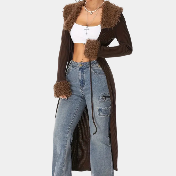 Vrouw in bruine lange jas met bontkraag en manchetten, witte crop top en wijde jeans. Modieuze herfstoutfit, casual streetwear stijl.